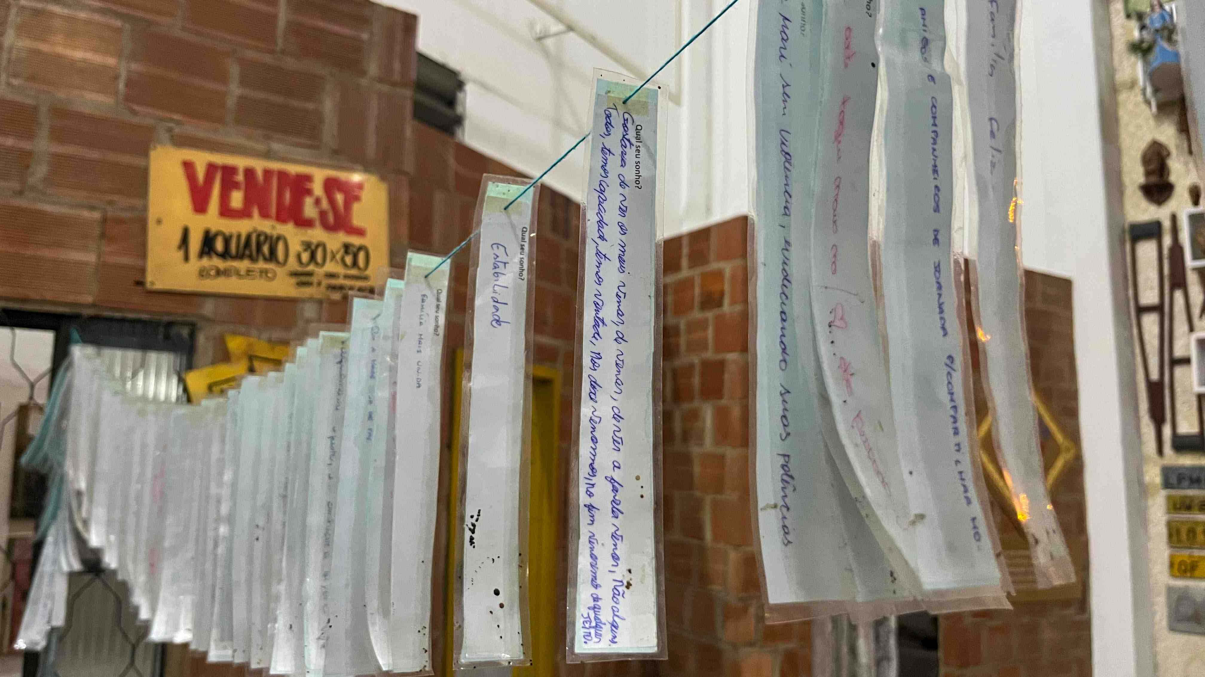 No Museu da Maré, uma pipa voa levando sonhos que deveriam ser direitos. Na rabiola, papeizinhos escritos por crianças da comunidade revelam desejos como ter uma casa segura, estudar em uma boa escola, se formar na faculdade e viver com dignidade. Pedidos simples que escancaram a ausência do básico.<br><strong>Foto: Maria Clara Vinhaes
