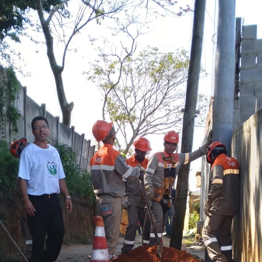 Funcionários da Light realizam instalação de novo poste de energia elétrica em área residencial, com acompanhamento de representante comunitário. A ação visa melhorar a infraestrutura e garantir mais segurança no fornecimento de energia para os moradores da região.